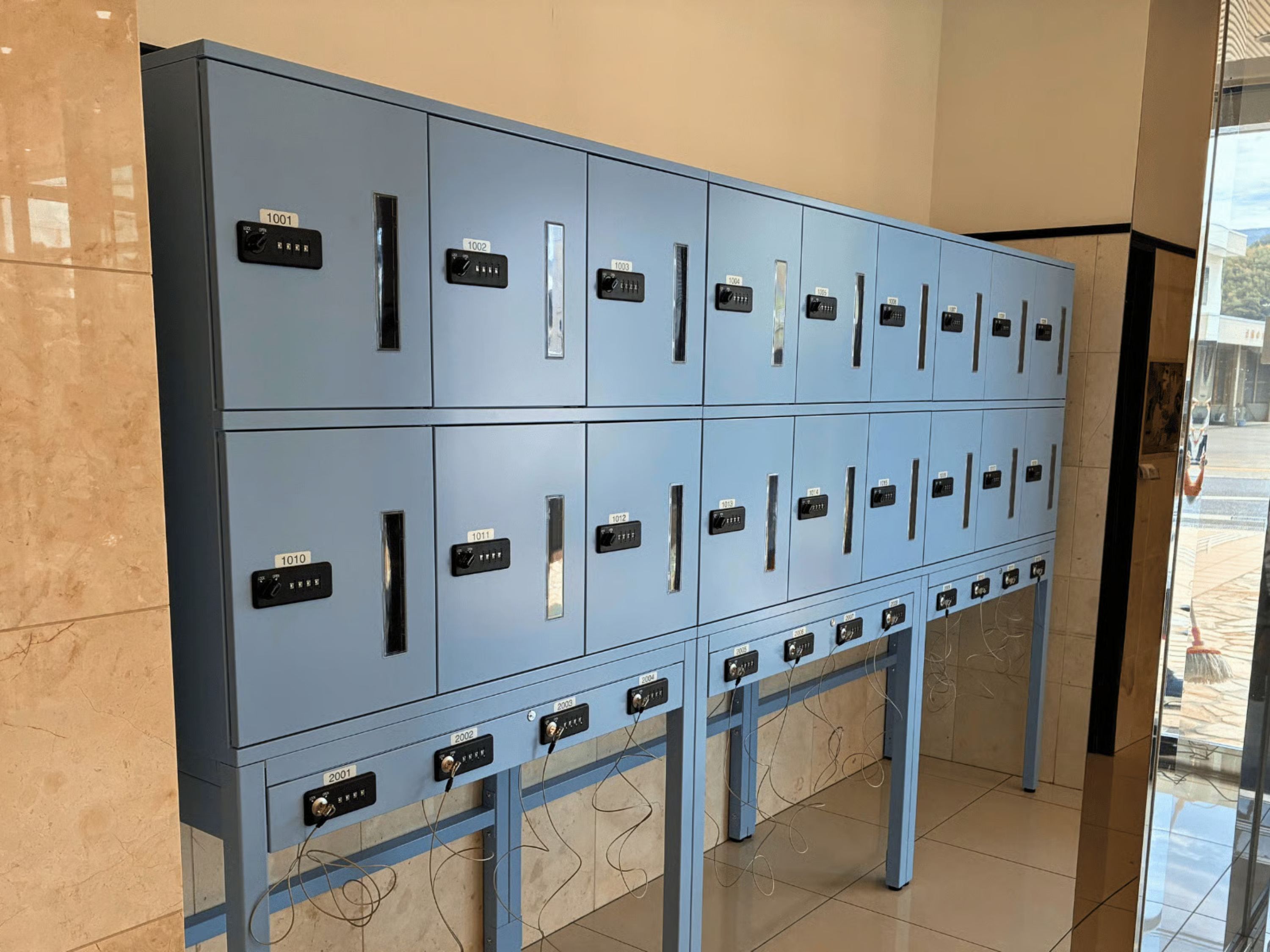 A row of blue lockers with numbered labels, indicating a secure storage area, possibly for guests' belongings.