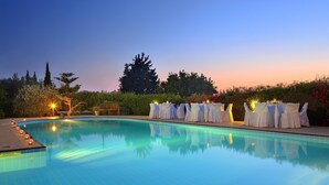 A swimming pool with a sunset view, surrounded by greenery and a covered seating area. - Nymfes Villas (Ermionida)