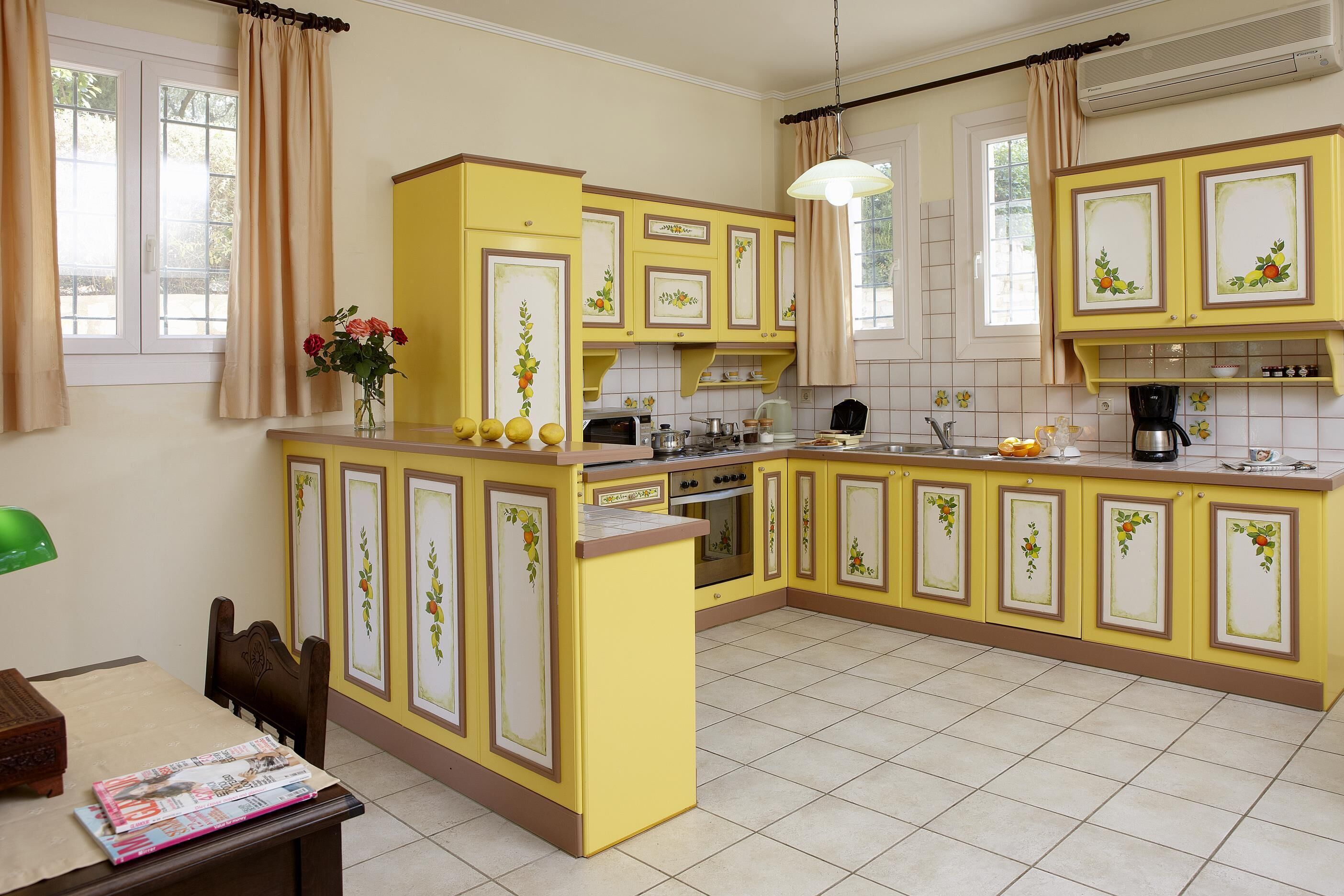 A kitchen with yellow cabinets, a dining table with chairs, and a window with curtains.