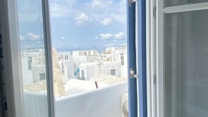 Ein Zimmer mit großem Fenster, einer Tür und Blick auf Gebäude.