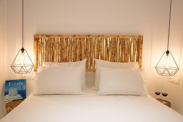 Habitación de hotel con una cama grande, dos mesitas de noche y un cabecero de madera.