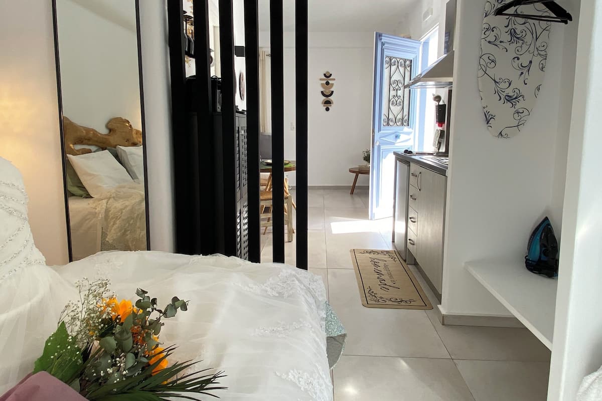 Een slaapkamer met een grote spiegel, een bed met bloemen, een kledingkast en uitzicht op de aangrenzende kamer.