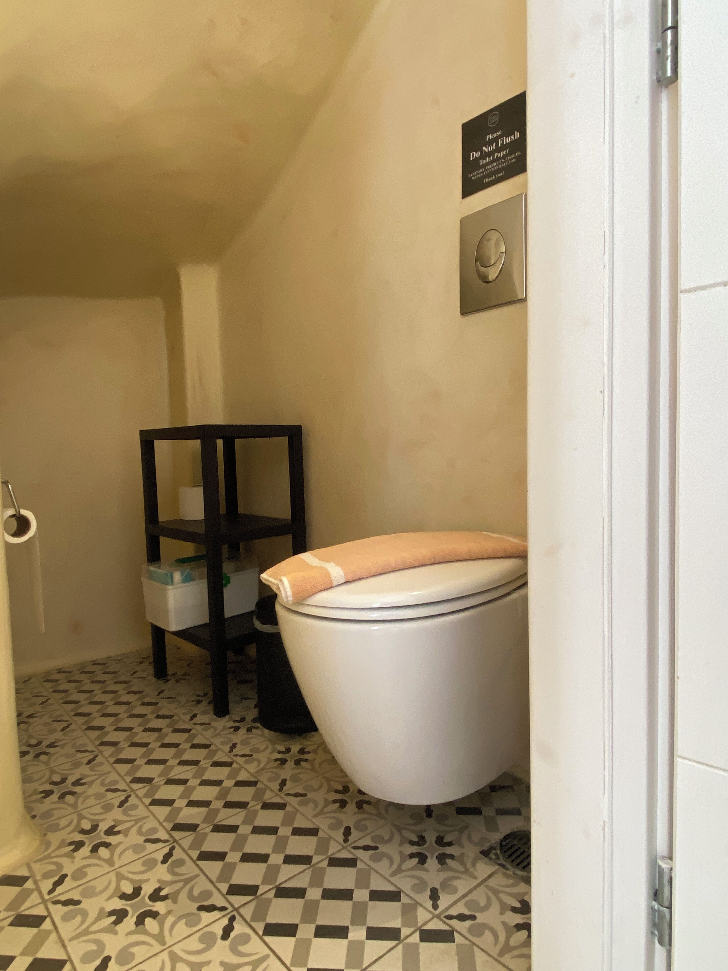 Un bagno piccolo con il water, uno scaffale con un asciugamano e il cartello 'Non gettare'.