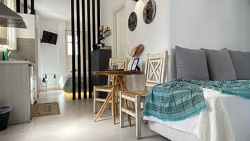 Un espacio habitable pequeño con cama, mesa de comedor y kitchenette.