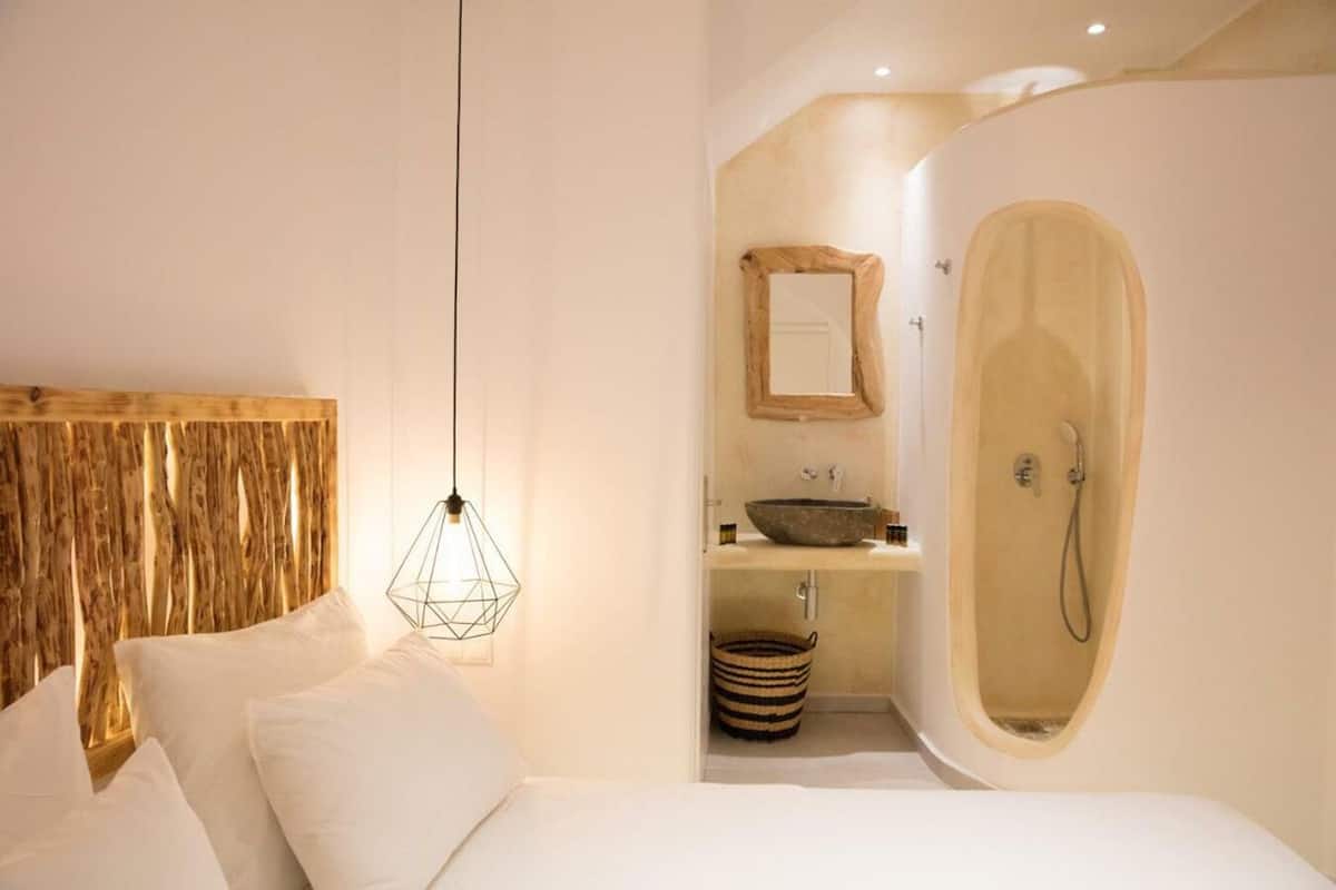 Een moderne slaapkamer met een houten hoofdeinde, een hanglamp, een inbouwsink en een ruime douche.