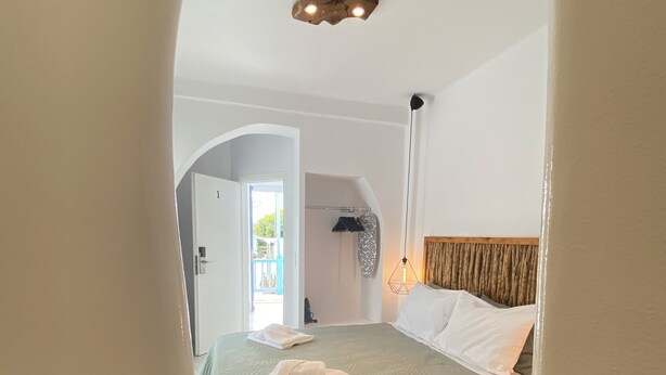 Ein Schlafzimmer mit Bett, Nachttisch, Pendelleuchte und Blick ins Freie.