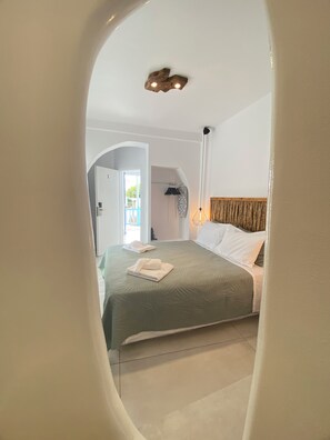 Un dormitorio con cama, una mesita de noche, una lámpara colgante y vistas al exterior.