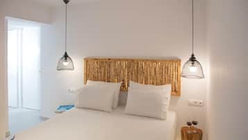 Een slaapkamer met een bed, twee hanglampen, een houten hoofdeinde en een nachtkastje met twee wijnglazen.