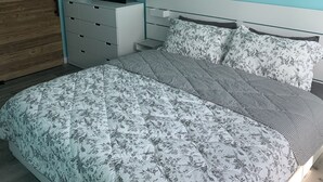 A bedroom with a bed, a dresser, a TV, and a wooden door.