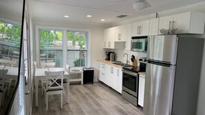 A modern kitchen with white cabinets, stainless steel appliances, and a dining area with white furniture.