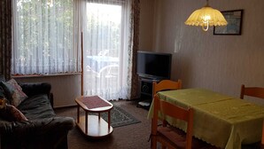 Un salon comprenant un canapé, une petite table, un téléviseur et une table à manger avec des chaises.