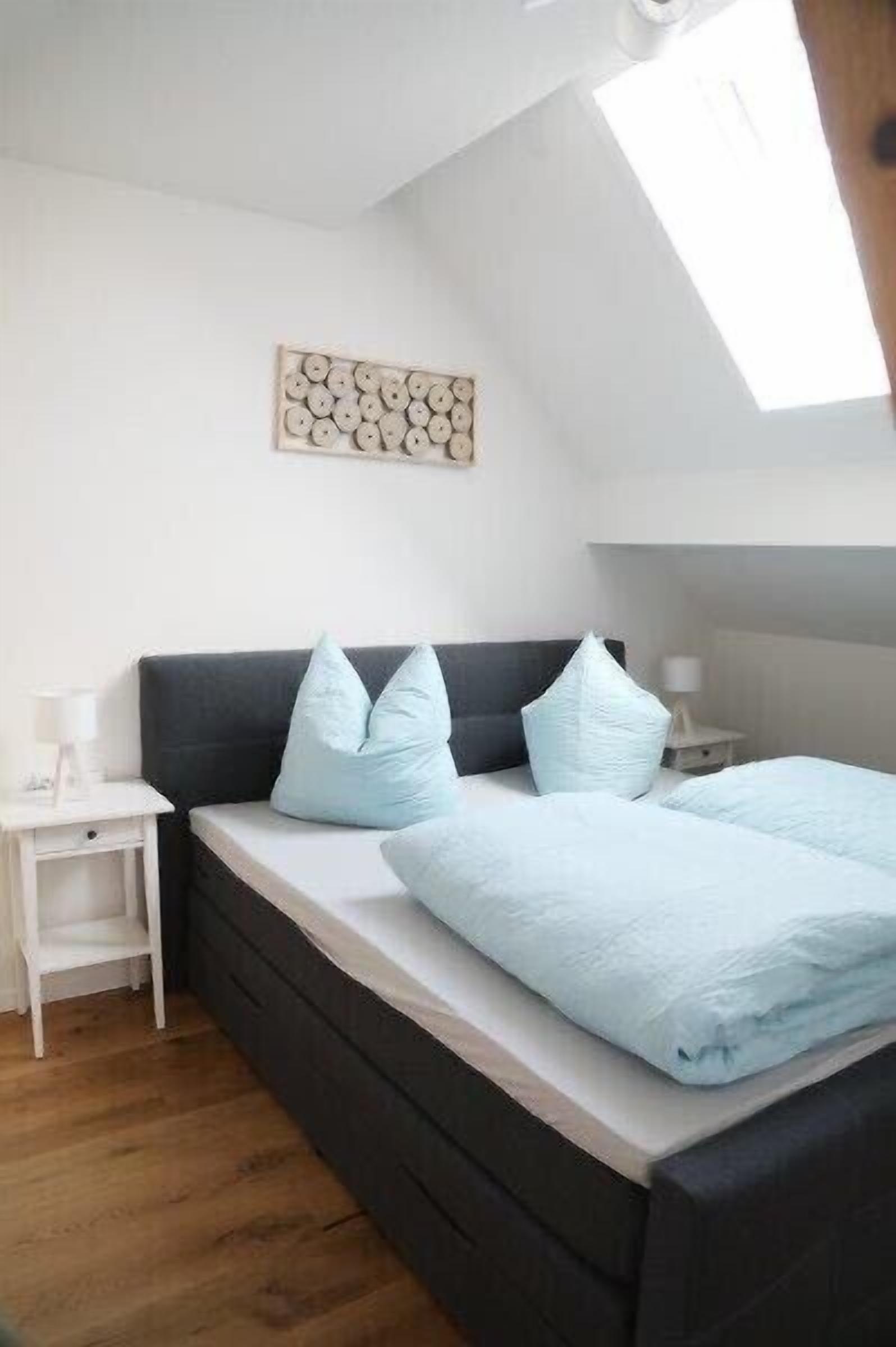 Ein Schlafzimmer mit einem Bett, einem Nachttisch, einem Wandbild und einem Oberlicht.