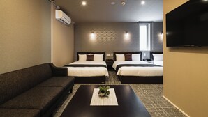 Une chambre d’hôtel avec deux lits, un canapé, un téléviseur à écran plat et une petite table agrémentée d’une plante.