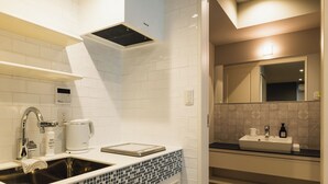 Une cuisine moderne avec des carreaux de céramique blancs disposés en motif métro, un évier en acier inoxydable, une machine à café et une hotte intégrée.