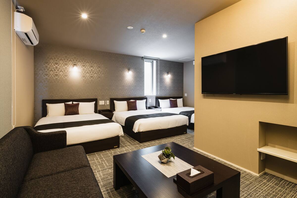 Ein Hotelzimmer mit zwei Betten, einem Flachbildfernseher, einem Sofa und einem Couchtisch.