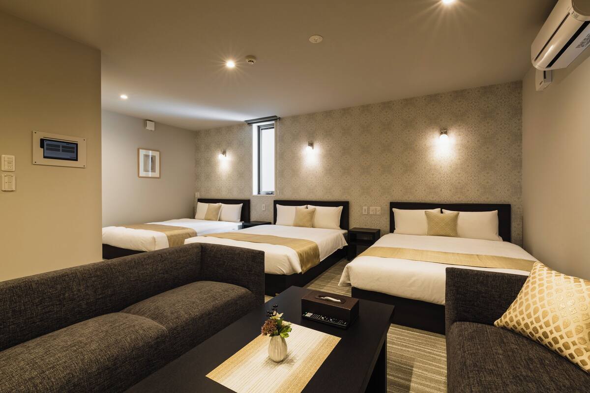 Ein Hotelzimmer mit zwei Betten, einem Schlafsofa, einem Couchtisch und einem kleinen Fenster.