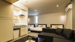 Une chambre d’hôtel moderne équipée d’une kitchenette, d’un canapé-lit et d’un grand lit.