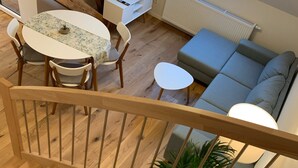 A modern living room with a staircase, a dining area, and a sofa. - Ferien auf Rüdlins Winzerhof (Auggen)