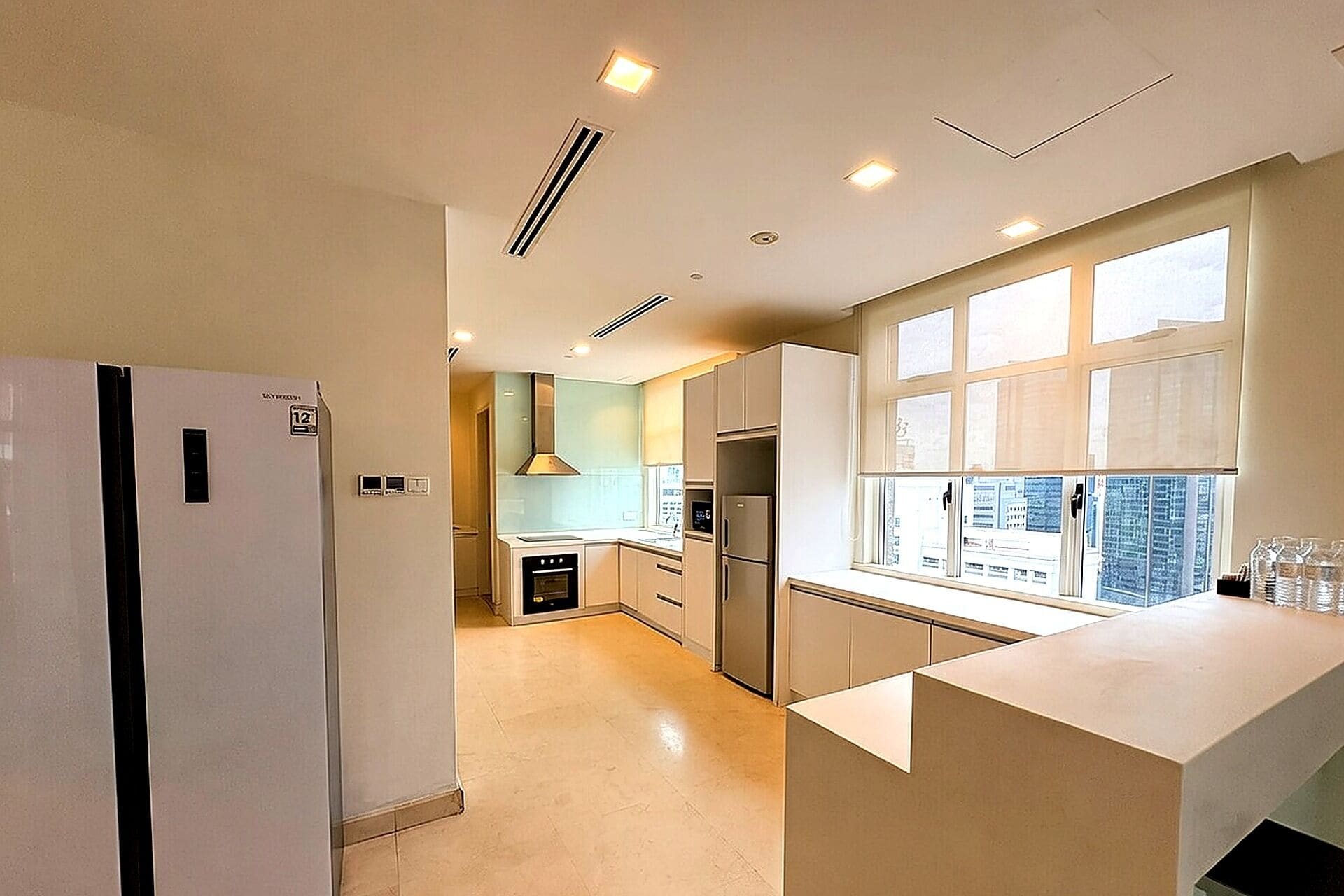 A modern kitchen with a built-in oven, a refrigerator, and a window with a view.