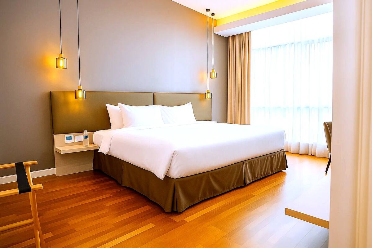 A modern hotel room with a large bed, bedside tables, and a view of the outdoors.