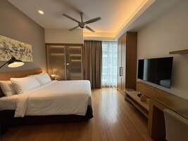 A hotel room with a bed, a TV, a ceiling fan, and a sliding door closet.