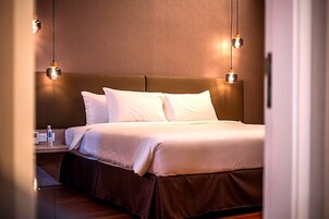 Una habitación de hotel con una cama, mesitas de noche y lámparas fijadas a la pared.