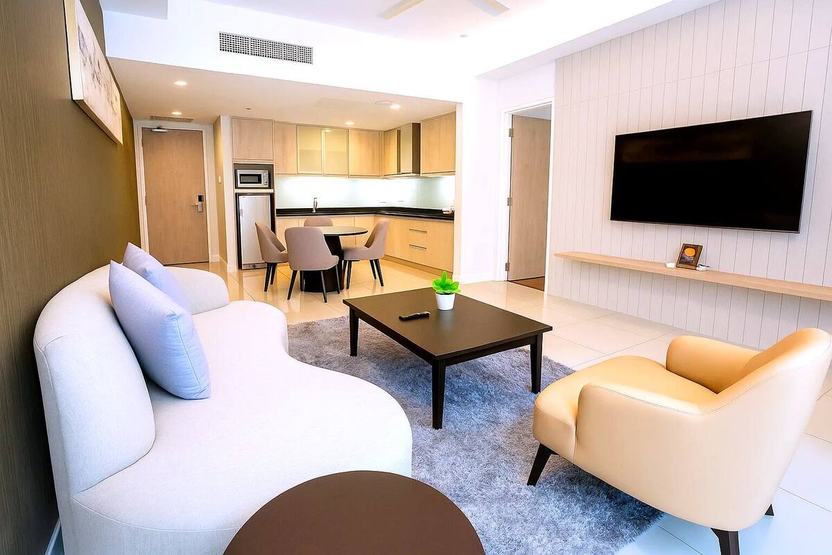 A modern living room with a sofa, a coffee table, and a TV mounted on the wall.