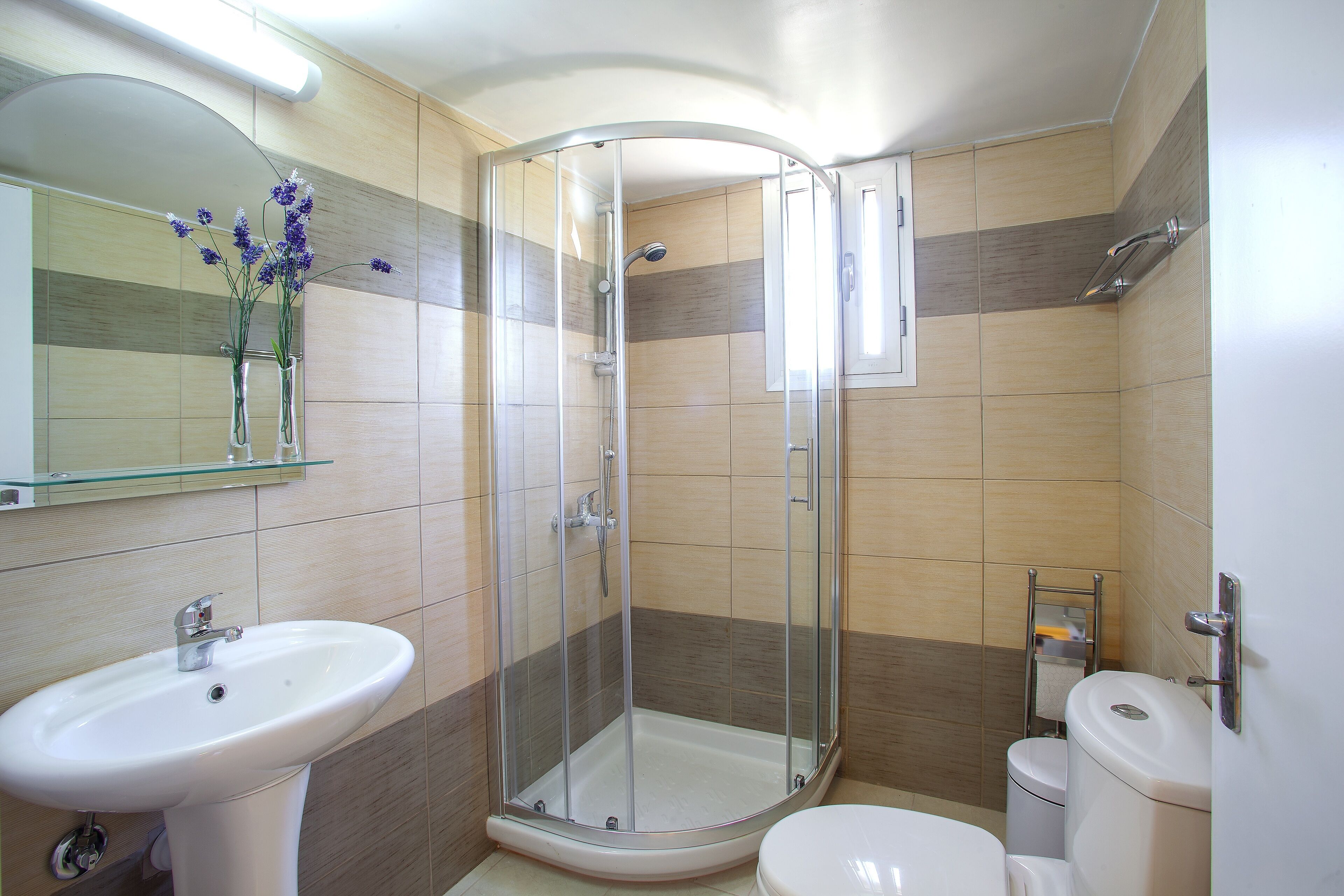 A bathroom with a glass-enclosed shower, a sink, and a toilet.
