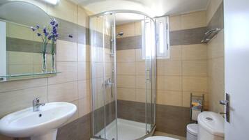 A bathroom with a glass-enclosed shower, a sink, and a toilet.
