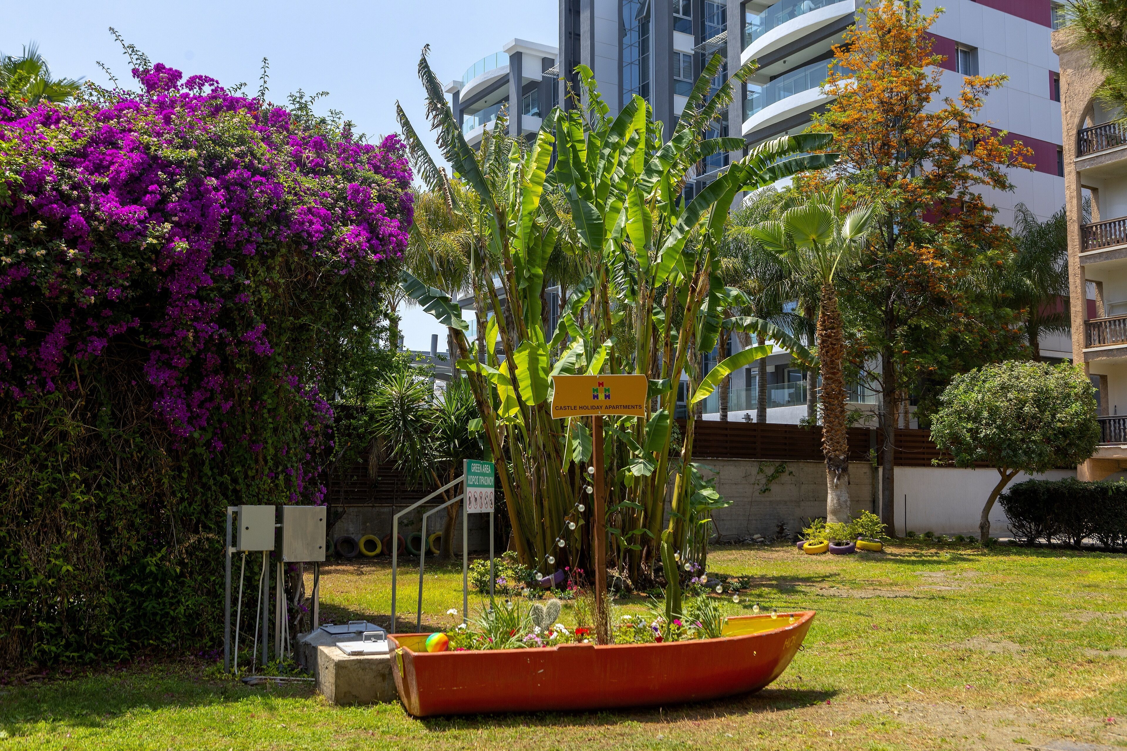 A garden with a sign indicating 'Castle Holiday Apartments'.
