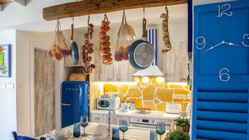 A kitchen with hanging garlic, a blue door with numbers, and a stone wall backsplash.