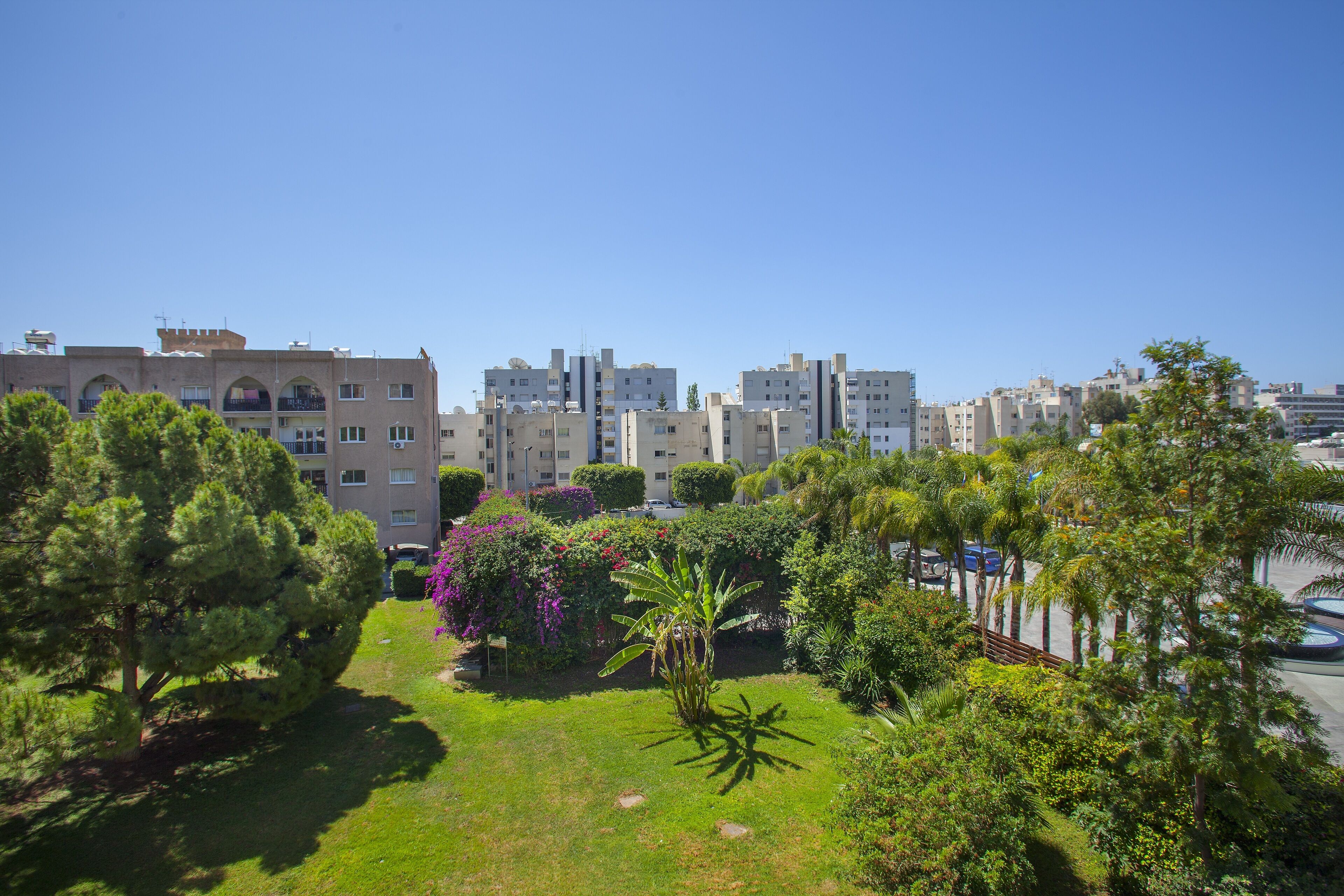 Un quartier résidentiel composé de plusieurs immeubles d’appartements, d’une végétation luxuriante et d’un ciel d’un bleu éclatant.