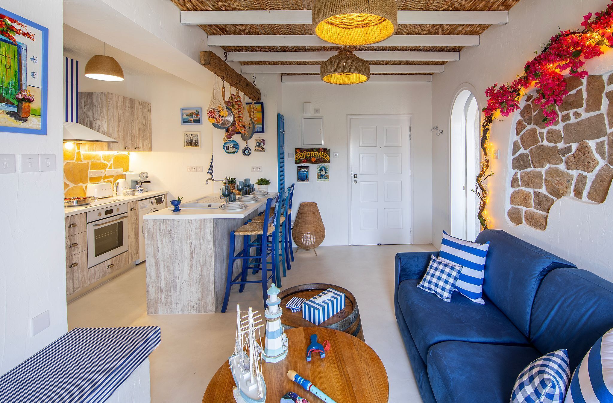 A modern kitchen with a central island, blue chairs, a blue sofa, and a stone wall.