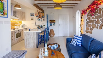 A modern kitchen with a central island, blue chairs, a blue sofa, and a stone wall.