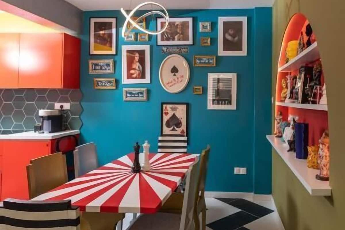 A dining area with a checkered tablecloth, striped chairs, and a wall decorated with framed pictures.
