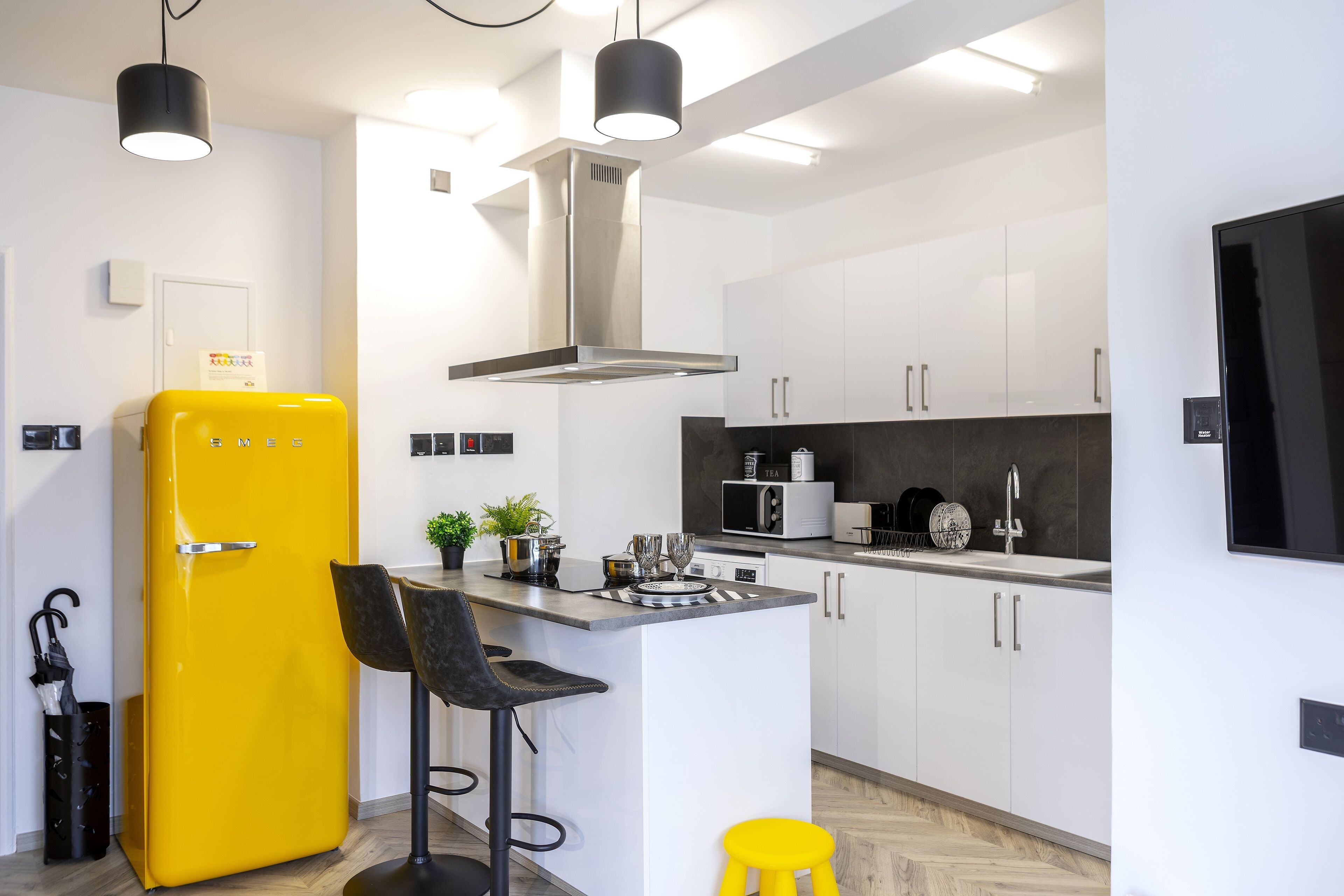 A modern kitchen with white cabinets, a yellow refrigerator, and a bar stool.