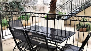 A patio area with a table and chairs, a staircase, and a concrete wall with greenery.