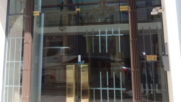 A building entrance with a large arched glass door, the number 52/54, and the name "LE PALAZZIO" visible.