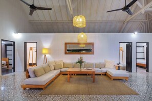 A modern living room with a sectional sofa, a coffee table, and a hanging light fixture.