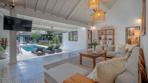A spacious living area with a pool view, modern furniture, and a flat-screen TV. - The Aryana Estate (Seminyak)