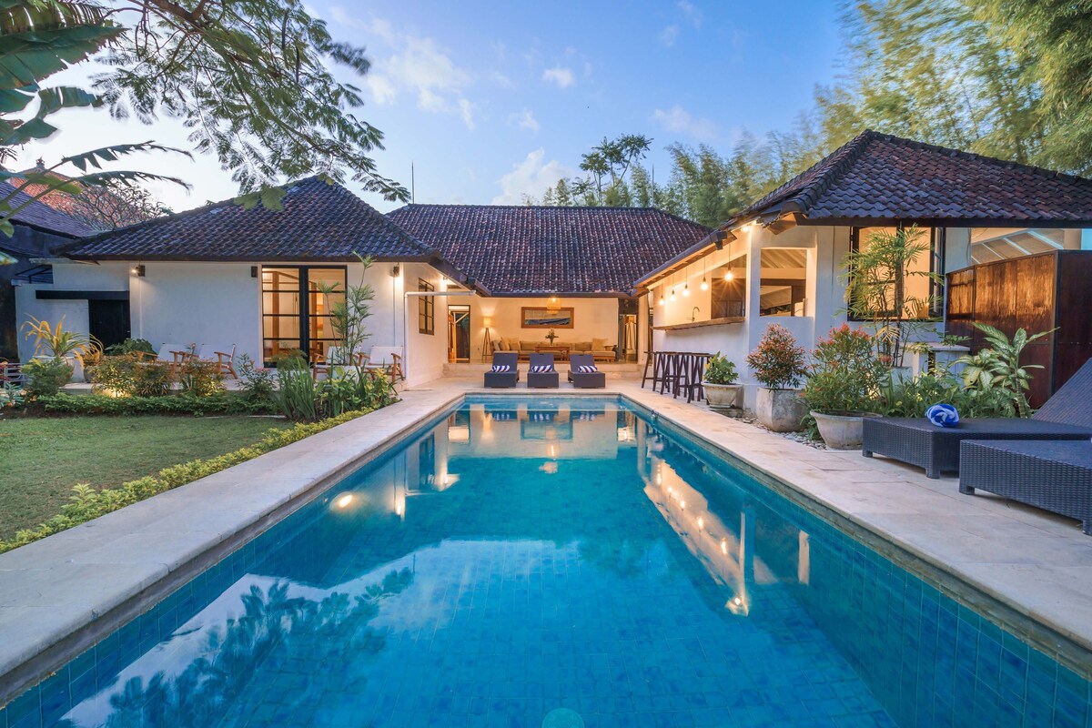 A residential property with a swimming pool, two houses, and a patio area.