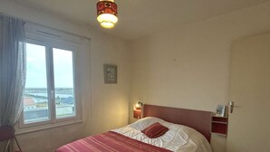 Un dormitorio con cama, ventana, mesita de noche y una silla.