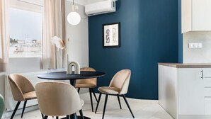 Een moderne keuken met een blauwe accentmuur, een ronde eettafel met stoelen en een raam met gordijnen.
