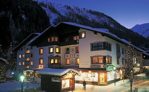 Un hotel grande de varios pisos con techo nevado y numerosas ventanas, situado en una zona montañosa.