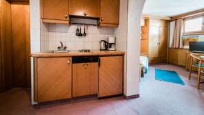 A compact kitchen with wooden cabinets, a dishwasher, and a coffee maker. - Appartement Christine by Skinetworks (Sankt Anton am Arlberg)