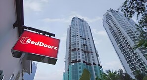 A RedDoorz sign, high-rise buildings, and a clear sky.
