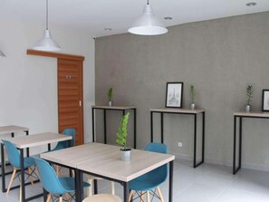 Un intérieur moderne avec une table à manger, des chaises, des luminaires suspendus et des plantes en pot.
