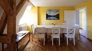 Un comedor con una mesa y sillas de madera, un cuadro en la pared y una puerta blanca.