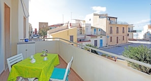 A balcony with a table set for two, overlooking a coastal street with buildings and a clear sky. - Appartamento Calipso (Santa Croce Camerina)