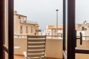 A balcony with a striped chair, a view of buildings, and a street lamp. - Appartamento Calipso (Santa Croce Camerina)